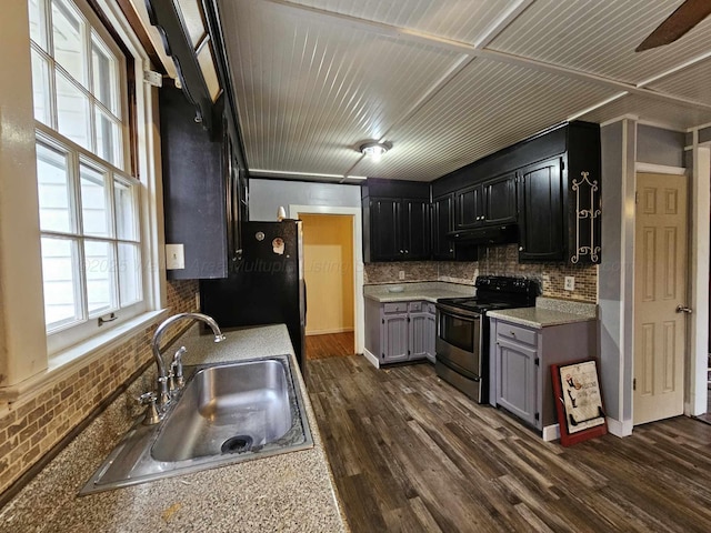 kitchen featuring sink, black refrigerator, dark wood-type flooring, and stainless steel range with electric stovetop