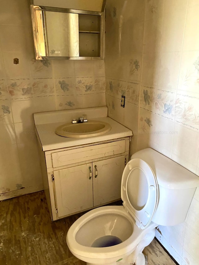 bathroom featuring toilet, vanity, and tile walls