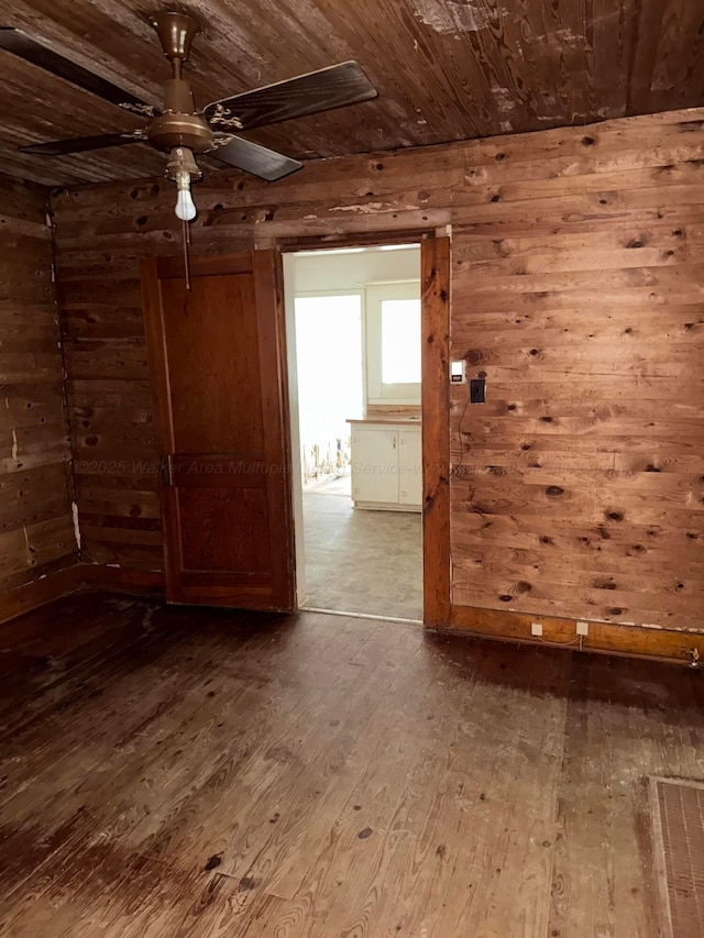 spare room with wood ceiling, wood-type flooring, wood walls, and a ceiling fan
