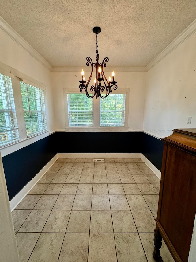 unfurnished dining area featuring a textured ceiling, a chandelier, ornamental molding, and light tile patterned floors