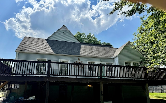back of house featuring a wooden deck and roof with shingles