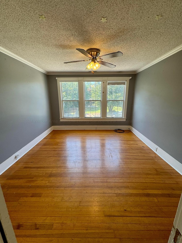 empty room featuring baseboards, crown molding, wood finished floors, and ceiling fan