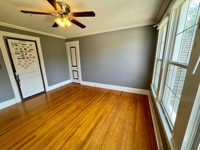 unfurnished room with a textured ceiling, wood finished floors, and crown molding