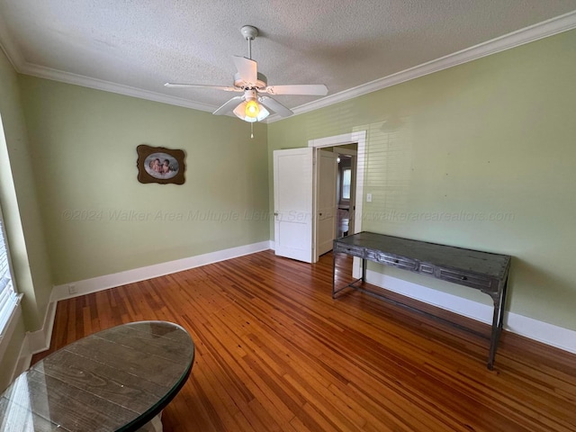 empty room with crown molding, baseboards, a textured ceiling, and wood finished floors