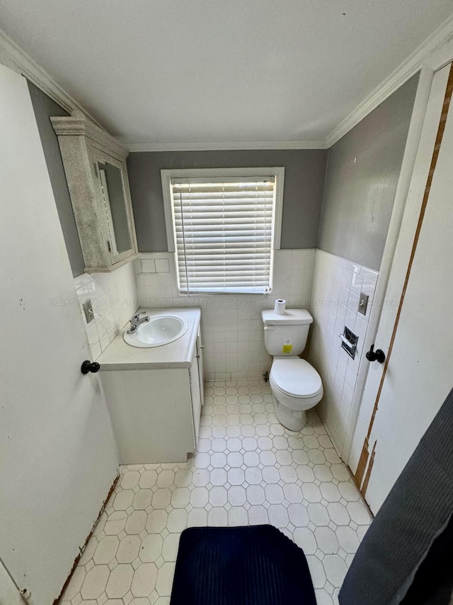 half bath featuring vanity, toilet, tile walls, and crown molding