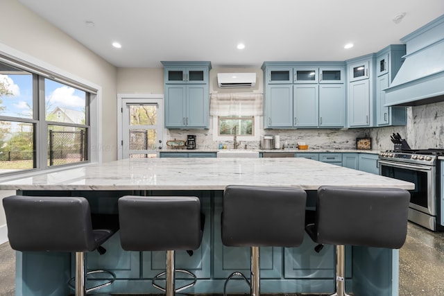 kitchen with stainless steel stove, backsplash, plenty of natural light, a spacious island, and a wall mounted air conditioner