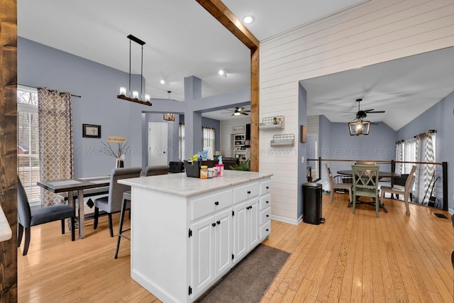 kitchen featuring light wood-type flooring, white cabinetry, ceiling fan with notable chandelier, and vaulted ceiling