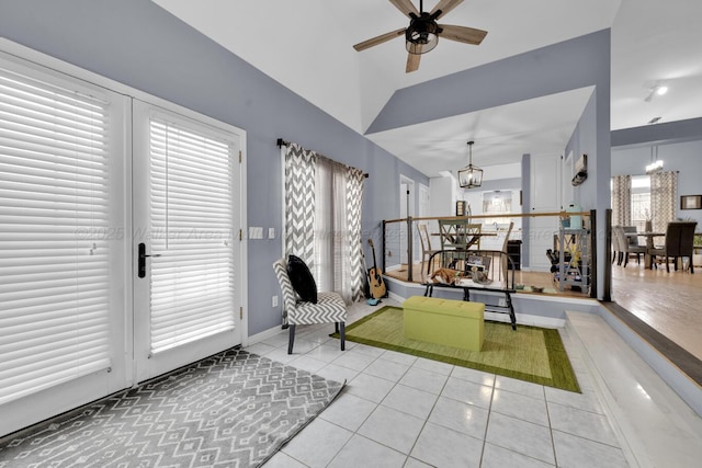 living area featuring lofted ceiling, light tile patterned flooring, and ceiling fan with notable chandelier