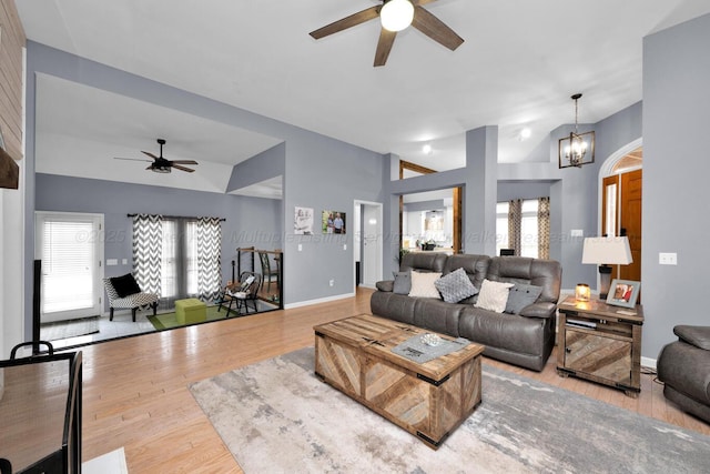 living room with baseboards, vaulted ceiling, ceiling fan with notable chandelier, french doors, and wood finished floors