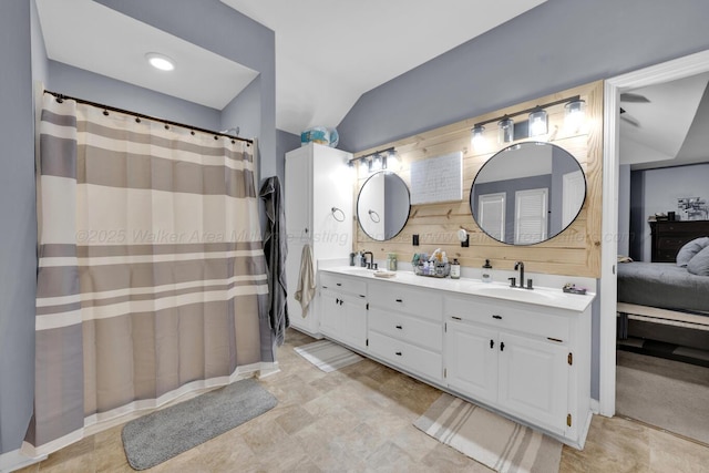 full bath with double vanity, connected bathroom, vaulted ceiling, and a sink