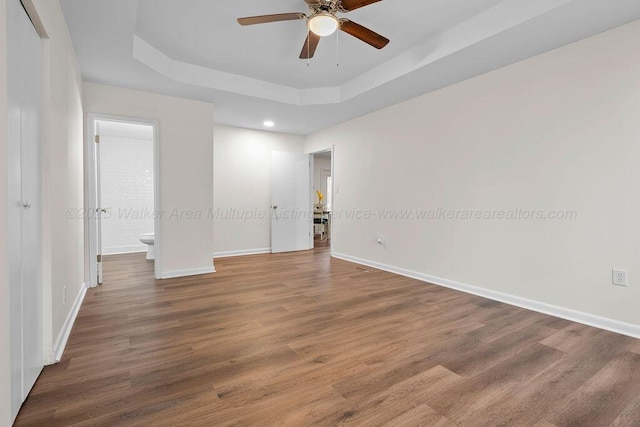 empty room featuring hardwood / wood-style floors, ceiling fan, and a raised ceiling