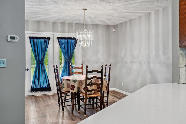 dining area featuring hardwood / wood-style flooring, a textured ceiling, and a chandelier