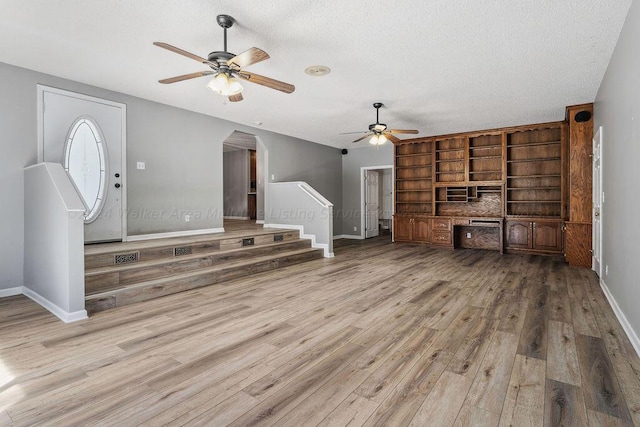 unfurnished living room with ceiling fan, a textured ceiling, and light hardwood / wood-style flooring