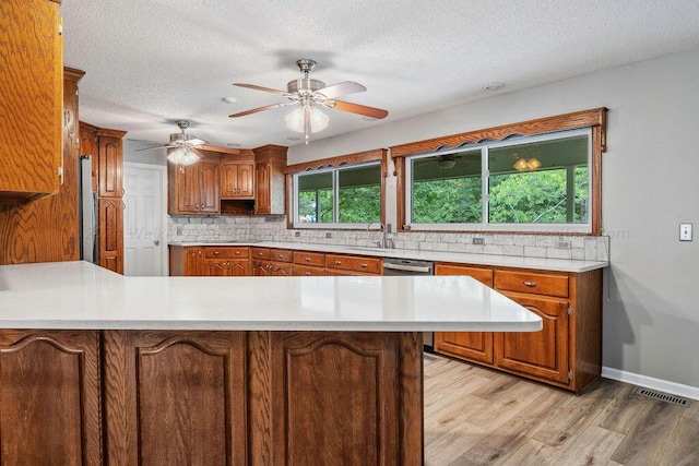 kitchen featuring backsplash, kitchen peninsula, light hardwood / wood-style floors, and a textured ceiling