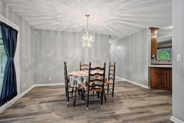 dining area with a chandelier, a textured ceiling, and hardwood / wood-style flooring