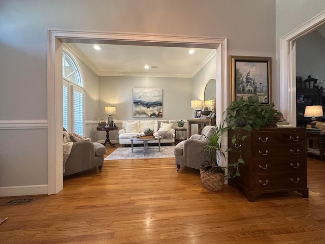 living area with ornamental molding and light hardwood / wood-style floors