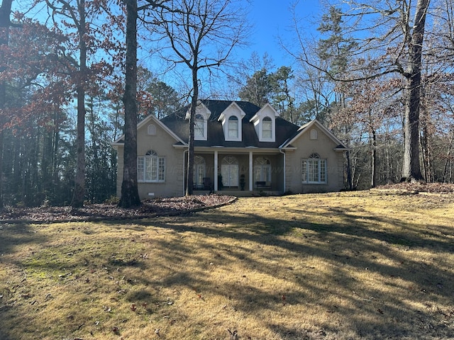 cape cod-style house with covered porch and a front lawn