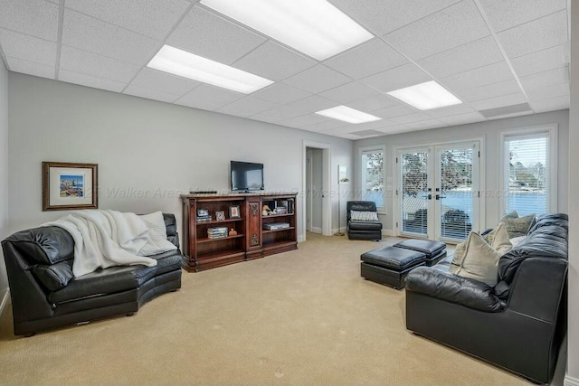 carpeted living area featuring french doors and a paneled ceiling