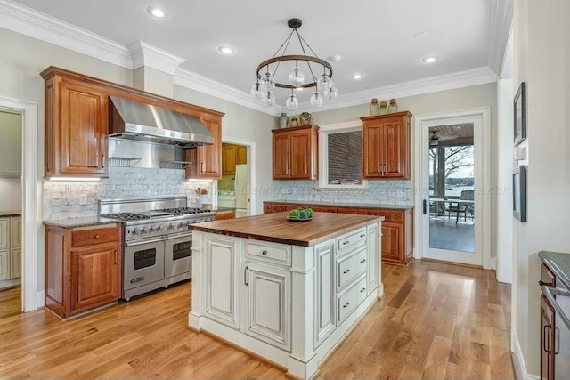 kitchen with range with two ovens, light wood-style flooring, butcher block countertops, and wall chimney exhaust hood