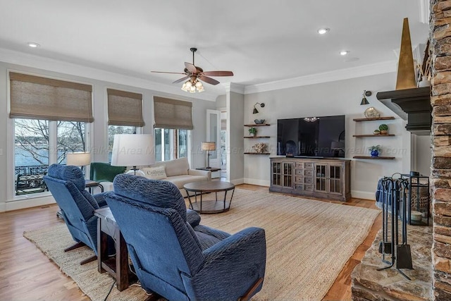 living room featuring ceiling fan, crown molding, baseboards, and wood finished floors