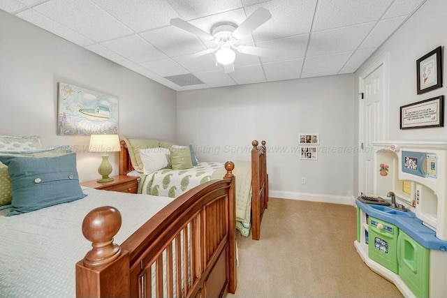 bedroom with a paneled ceiling, light carpet, baseboards, and a ceiling fan