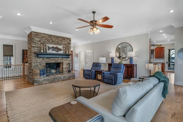 living area with recessed lighting, a fireplace, light wood-type flooring, and ornamental molding