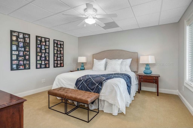 bedroom with a drop ceiling, baseboards, and light colored carpet