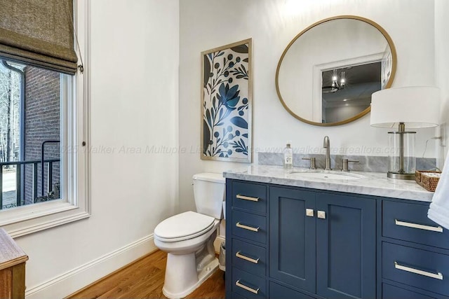 bathroom with vanity, toilet, wood finished floors, and baseboards