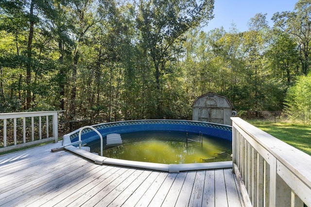 view of swimming pool featuring a wooden deck and a shed