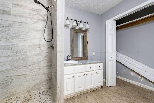 bathroom with a shower, vanity, a textured ceiling, and hardwood / wood-style flooring