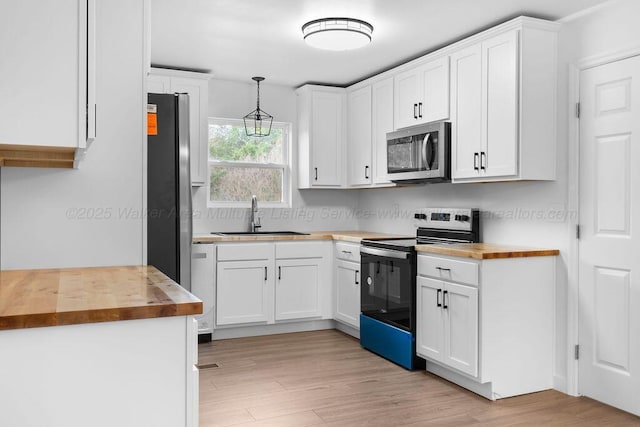 kitchen with wood counters, pendant lighting, electric range, and sink