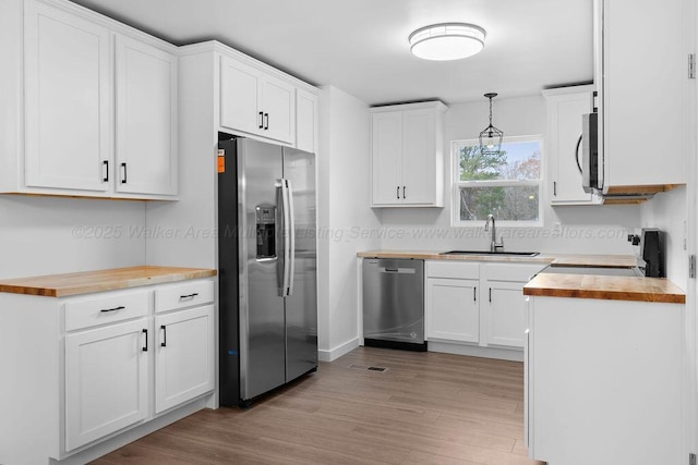 kitchen featuring butcher block countertops, white cabinets, sink, and appliances with stainless steel finishes