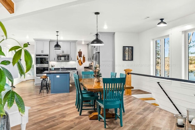 dining area featuring light hardwood / wood-style flooring and beamed ceiling