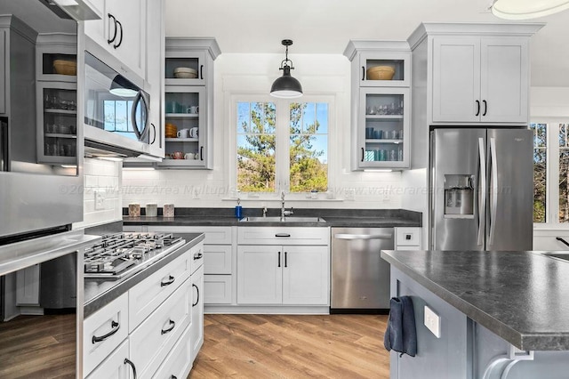 kitchen with hanging light fixtures, sink, hardwood / wood-style floors, decorative backsplash, and stainless steel appliances