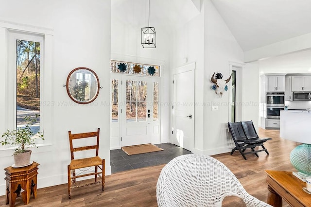 foyer entrance featuring high vaulted ceiling, dark hardwood / wood-style floors, and an inviting chandelier