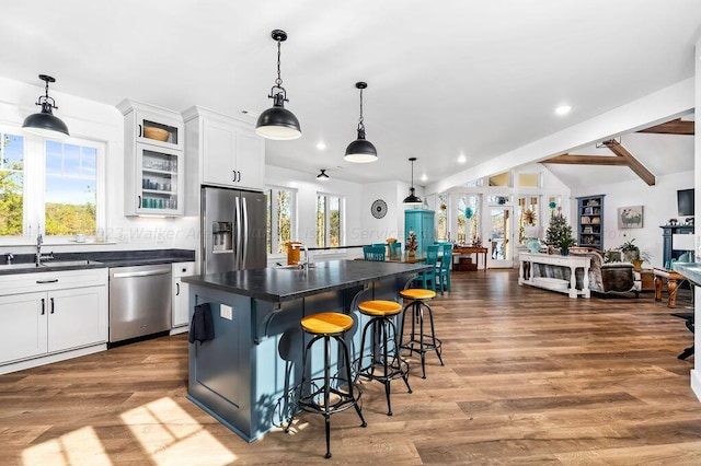 kitchen featuring white cabinets, a kitchen island, stainless steel appliances, sink, and a breakfast bar area