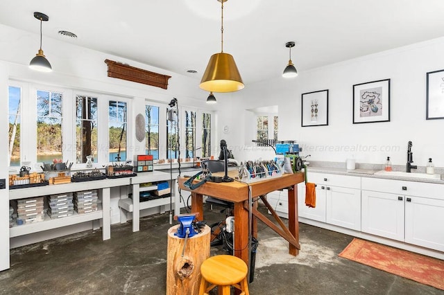 kitchen with decorative light fixtures, sink, white cabinets, and plenty of natural light