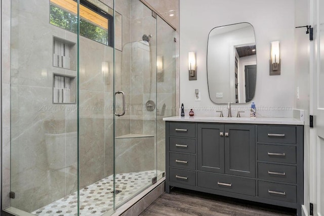 bathroom featuring wood-type flooring, a shower with door, and vanity