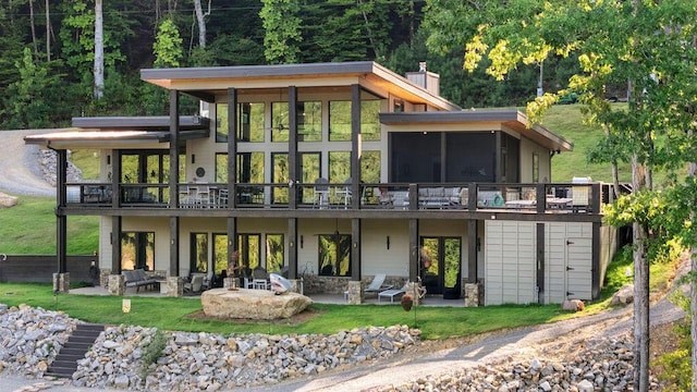 back of house featuring an outdoor living space, a deck, a patio, and a sunroom