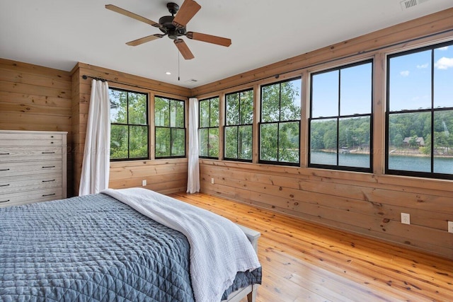 bedroom with ceiling fan, hardwood / wood-style floors, and wood walls