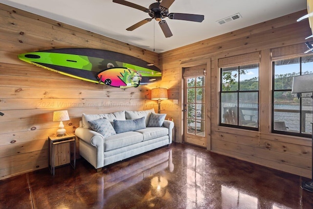 living area featuring wood walls and ceiling fan