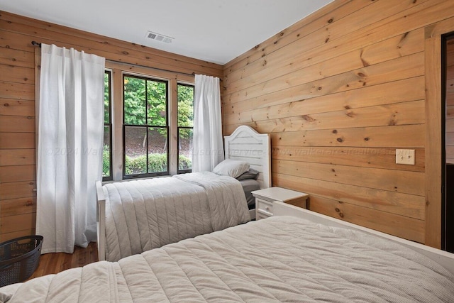 bedroom featuring hardwood / wood-style floors and wooden walls