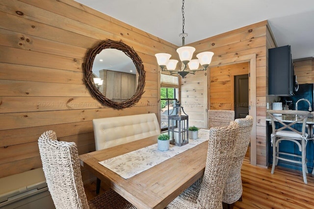 dining room featuring wood walls, hardwood / wood-style floors, and an inviting chandelier