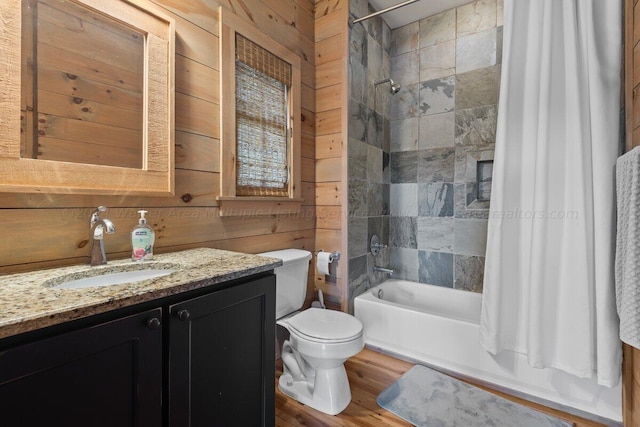 full bathroom featuring shower / tub combo, vanity, wooden walls, wood-type flooring, and toilet