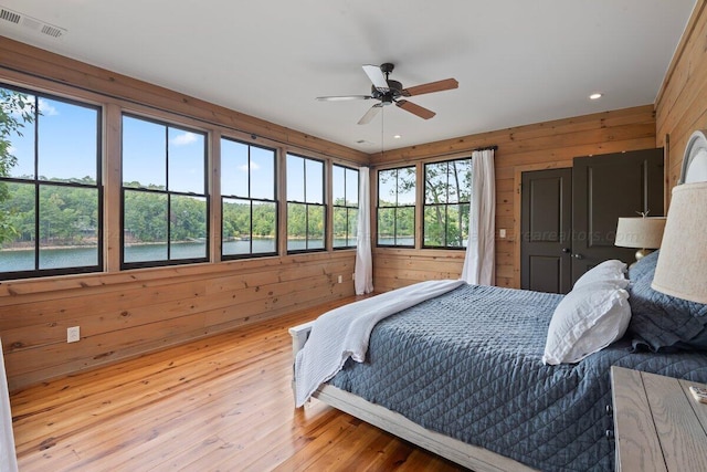 bedroom featuring hardwood / wood-style floors, ceiling fan, and wood walls