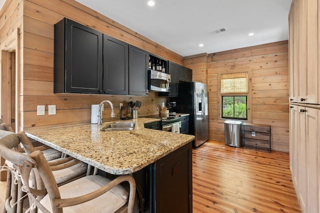 kitchen with sink, stainless steel appliances, kitchen peninsula, light hardwood / wood-style floors, and a breakfast bar area