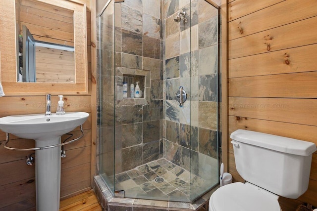 bathroom featuring hardwood / wood-style floors, wood walls, toilet, and a shower with shower door