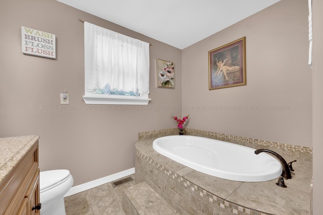 bathroom with tiled tub, vanity, and toilet