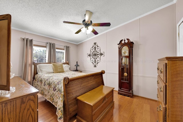 bedroom featuring a textured ceiling, ceiling fan, light wood-type flooring, and ornamental molding