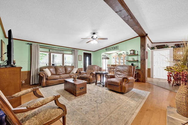 living room with ceiling fan, ornamental molding, a textured ceiling, and light wood-type flooring